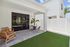 Charming outdoor patio with modern furniture, lush greenery, and sleek glass doors, perfect for relaxing or entertaining.