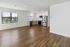 Bright open-plan living space with elegant wood floors, contemporary kitchen, and large window view.