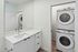 Modern bathroom with elegant vanity mirror and in-unit laundry featuring sleek stackable washer and dryer.