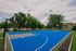 Modern outdoor basketball court nestled in a vibrant community setting, surrounded by lush greenery and contemporary homes, under a clear blue sky.