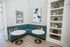 Chic corner nook with a teal banquette, elegant round marble tables, and tasteful decor in a cozy setting.
