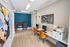 Modern co-working space with stylish decor, featuring two computer workstations, comfortable seating with a round table, and vibrant artwork.