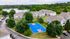 Charming residential community surrounded by lush greenery and a tranquil lake, featuring modern apartments with picturesque balconies and a vibrant blue basketball court.