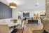 Elegant open-plan living space featuring sophisticated dining area, plush seating, and stylish modern decor with warm lighting and decorative stone accents.
