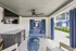 Chic outdoor lounge area featuring modern seating, a sleek TV, granite countertops, and views of a refreshing pool with stylish blue umbrellas.