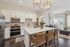 Contemporary kitchen with sleek white cabinets, luxurious island seating, and elegant gold lighting fixtures. Bright and inviting open-concept living space with modern decor and abundant natural light.