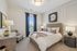 Elegant bedroom with plush beige bed, stylish decor, and natural light filtered through chic navy drapes.