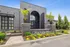 Elegant entrance of a modern apartment complex with stylish brick architecture, lush landscaping, and vibrant flowerbeds creating an inviting atmosphere.