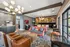 Luxurious apartment lounge featuring a cozy seating area with vibrant sofas, stylish artwork on brick walls, elegant lighting fixtures, and classic leather chairs for a warm, welcoming atmosphere.