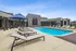 Luxurious apartment complex pool area featuring stylish loungers, elegant blue umbrellas, and modern architecture, perfect for relaxation and leisure.