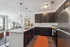 Modern kitchen with sleek granite countertops, elegant pendant lighting, and rich dark cabinets, opening onto a bright living area with stylish decor.
