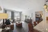 Chic apartment interior featuring a cozy living area with large windows, an elegant sitting arrangement, and a sleek granite kitchen counter beside a stylish bedroom entrance.