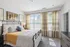 Bright and inviting bedroom featuring a large bed with stylish bedding, natural light streaming through elegant curtains, and tasteful wall art for a cozy atmosphere.