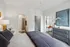 Bright and cozy bedroom with modern decor, open doorway to a stylish bathroom, and a peek into a chic kitchen with elegant lighting.