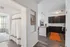 Modern apartment interior showcasing a sleek kitchen with dark cabinets and an inviting living area, highlighted by chic lighting and stylish decor.