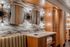 Elegant bathroom design with geometric mirrors, warm wood cabinetry, and modern sconce lighting, offering a luxurious ambience.