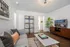 Contemporary living room with chic gray sofa, stylish coffee table, and elegant decor. Features a lush plant, modern shelving, and a sleek entertainment unit with a flat-screen TV.