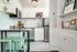 Chic modern kitchen with sleek stainless steel appliances, elegant white cabinetry, and vibrant mint green bar stools, perfect for contemporary living.