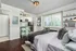 Charming studio apartment featuring a cozy bed, sleek kitchenette with modern fixtures, and sunlit windows overlooking lush greenery.
