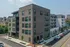 Modern urban apartment building with stylish brick and contemporary design, located at a vibrant corner in a bustling neighborhood.