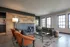 Modern living room with stylish wood-paneled accent wall, plush seating, and abundant natural light through large windows.