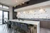 Modern kitchen with sleek island, stylish bar stools, geometric backsplash, and elegant lighting in a contemporary apartment.