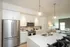Modern open-concept kitchen with sleek stainless steel appliances, elegant pendant lighting, and cozy living area with natural light.