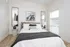 Elegant bedroom with contemporary decor, featuring a cozy bed framed by stylish mirrors and natural light from large windows.