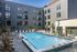 Modern apartment complex with inviting outdoor pool and stylish sun loungers, surrounded by sleek architectural design.