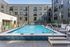 Modern apartment complex featuring a sparkling outdoor pool surrounded by sleek architecture and lush greenery.