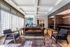 Elegant modern living room with chic leather sofa, stylish armchairs, and a glass coffee table on a patterned rug, featuring floor-to-ceiling windows and contemporary lighting.