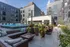 Luxurious urban courtyard featuring a sparkling pool, elegant lounge area, and lush greenery in a modern apartment complex.