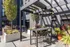 Modern outdoor patio with sleek pergola and stylish seating area surrounded by lush greenery, ideal for relaxing and entertaining.