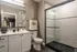 Elegant bathroom featuring sleek glass shower, modern vanity with large mirror, and stylish decor accents.