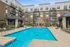 Chic apartment complex featuring a refreshing outdoor pool, stylish lounge chairs, and modern balconies surrounded by lush greenery.