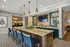 Elegant modern kitchen with a large marble island, plush navy chairs, and stylish pendant lighting, offering a sophisticated dining experience.