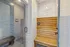 Elegant modern sauna with sleek glass door and warm wood seating, surrounded by stylish tile walls.