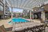 Luxurious apartment complex featuring a sparkling outdoor pool, stylish cabanas, and spacious lounging areas under a chic pergola.