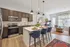 Contemporary open-concept kitchen and living area featuring sleek dark cabinets, stylish island with seating, and vibrant decor.