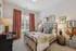 Charming bedroom with elegant decor, featuring a comfortable bed adorned with vibrant floral cushions, soft lighting, and stylish artwork for a cozy atmosphere.