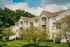 Charming apartment complex featuring elegant stone accents and lush green landscaping under a bright blue sky.