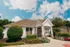 Charming white suburban home with a gabled roof, beautifully landscaped garden, and a welcoming front entry under a bright blue sky.