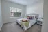 Bright and cozy bedroom featuring a plush bed with decorative pillows, elegant side tables, and a sunlit window offering garden views.