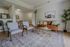 Inviting living room with modern decor featuring a cozy leather sofa, stylish armchairs, and a chic glass coffee table, complemented by a tranquil dining area and a sleek kitchen bar.