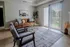 Inviting living room with cozy brown leather sofa, chic glass coffee tables, and abundant natural light from sliding glass doors.