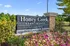 Charming Honey Creek Apartments sign surrounded by vibrant flowers against a clear blue sky.