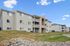 Charming multi-story apartment complex with modern balconies and lush greenery under a clear blue sky.