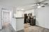 Chic modern kitchen with stainless steel appliances, sleek cabinetry, and stylish tile backsplash, adjacent to an inviting hallway with plush carpeting.