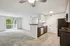 Bright open-concept apartment with modern kitchen, elegant cabinetry, and a spacious living area featuring sliding glass doors to a lush view.