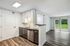Modern kitchen with sleek cabinetry and stainless steel appliances, opening to a bright living area with large sliding doors to a lush green view.